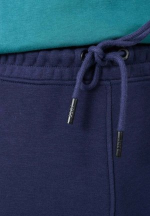Pantalones de chándal azul marino con cordón en la cintura, que presentan una textura suave y costuras reforzadas a lo largo de las costuras.