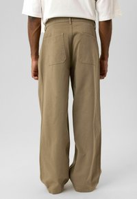 Khakikleurige broek met brede pijpen, een hoge taille, twee achterzakken en een gemêleerde katoenmix, ontworpen voor comfort en casual gebruik.