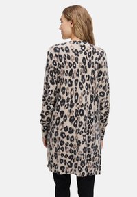 Dlhý krémový cardigan s leopardím vzorom v hnedej a čiernej farbe. Mäkká textúra, otvorený predok a voľný strih.