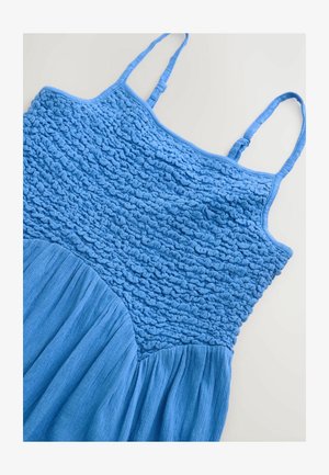 Mėlyna suknelė su tekstūruotu korsetu, kuriame yra susiraukšlėta medžiaga ir lygi išsiplėtusi sijonas. Plonos reguliuojamos petnešėlės papildo dizainą.