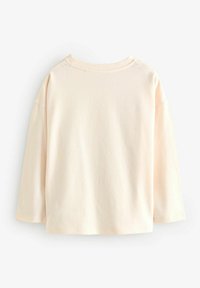 Haut long à manches en pêche clair, fabriqué en tissu doux. Coupe décontractée avec un col rond et des coutures d'épaules tombantes. Texture lisse, sans motifs visibles.
