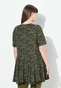 Vestido corto de manga corta negro y verde oliva con diseño plisado, que presenta un patrón de puntos y un escote redondo, visto desde la parte de atrás.