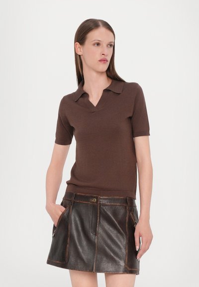 Polo shirt marron à manches courtes avec un col en V et une coupe slim, associé à une minijupe en cuir marron avec poches avant et surpiqûres contrastées.
