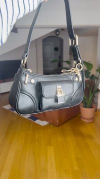 Sort læderhåndtaske med gulddetaljer, lynlåslukning og forlommer med låsebeslag. Har en kort rem til bæretaske.