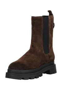 Botín de ante marrón con panel lateral elástico negro y tira de agarre. Suela negra gruesa con borde estriado, con acabado mate.