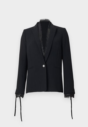 Blazer noir sur mesure avec un seul bouton décoratif, bordure en dentelle le long du col et des poignets, et des rubans attachés aux manches.