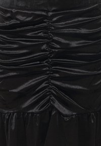 Tessuto di satin nero con arricciature verticali lungo il centro e un orlo arricciato in basso.