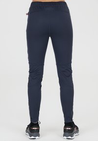 Marina atletiska leggings med en åtsittande design, tillverkade av stretchigt material. Har dragkedjor vid anklarna och ett elastiskt midjeband för komfort.