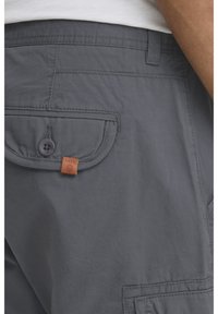 Grijze cargoshorts met een flapzak met knoopsluiting, leren labelaccent en zichtbare stiksels. Gestructureerde stof.