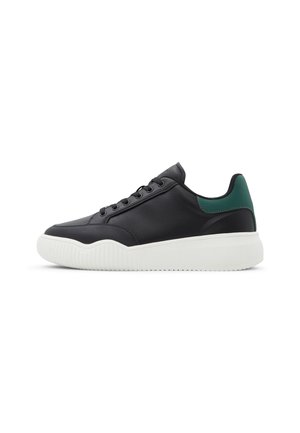 Black leather sneaker with white textured sole and green accent at heel. Features a rounded toe and lace-up design.