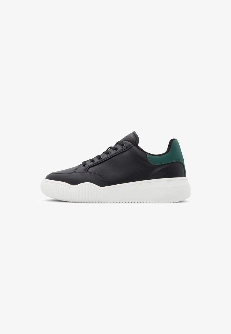 Black leather sneaker with white textured sole and green accent at heel. Features a rounded toe and lace-up design.