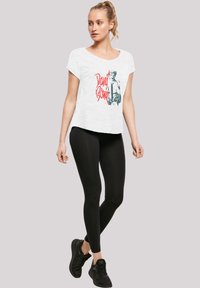 White, short-sleeve t-shirt with a David Bowie graphic in red and black, paired with black leggings and black athletic shoes.