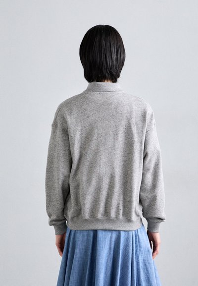 Gray fleece sweater with ribbed waistband and cuffs, featuring a collared neckline. Pairing with a blue pleated skirt.