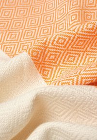 Geweven stof met een oranje ruitpatroon en een textuur van crèmekleurige sectie, met zachte, gladde texturen en uitgesproken kleuren.