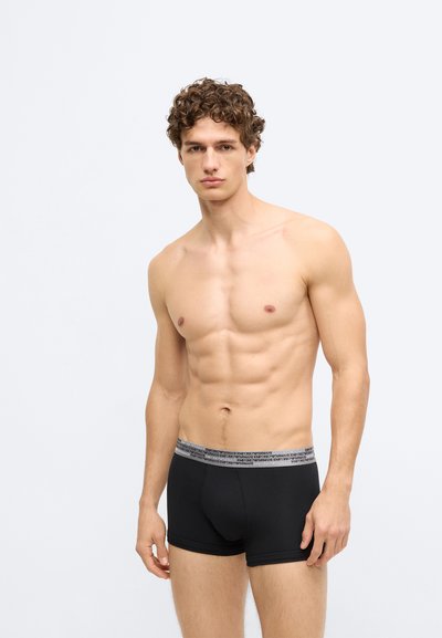 Fekete boxeralsó szürke elasztikus derékpánttal, melyen márkajelzés található. Simas textúra, testhezálló szabás és combközépig érő hosszúság.