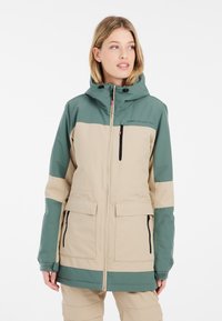 Beige und grüne wasserdichte Jacke mit einem Reißverschluss vorne, großen Taschen, verstellbarem Kapuzen und kontrastierenden Farbblöcken an den Ärmeln.
