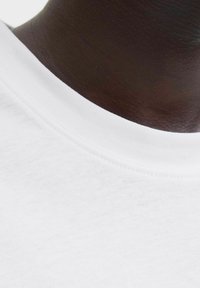 Hvid bomulds t-shirt med en glat rund udskæring. Nærbillede viser tekstur og syningsdetaljer på kraven.