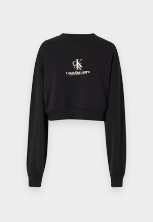 Črna skrajšana sweatshirt iz mehkega materiala, z okroglo ovratnikom in dolgimi rokavi. Prikazuje logotip "CK Calvin Klein Jeans" v beli in zlati barvi.