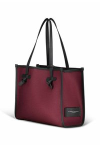 Bordeaux totebag met zwarte hardware, gemaakt van een gestructureerd materiaal, met twee lange handvatten en decoratieve knopen aan elke kant.