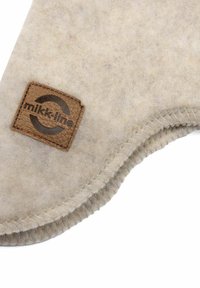 Siva filcana tkanina s mekšom teksturom, s okruglim kožnim zakrpom na kojoj je urezan natpis "mikk-line". Zakrivljeni rub s vidljivim detaljima šavova.