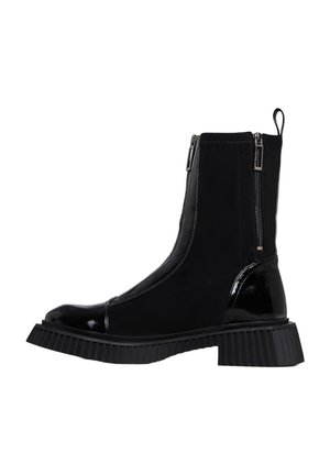 Schwarzer Stiefel bis zur Mitte der Wade mit grober profillierter Sohle, glänzenden Zehen- und Fersenakzenten, doppeltem silbernem Reißverschluss an der Seite und Zuglasche hinten.