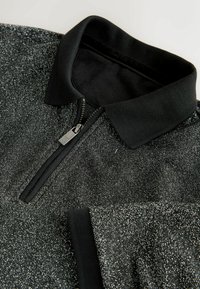 Czarny podkoszulek polo z teksturowanym, błyszczącym wykończeniem, z zamkiem błyskawicznym z przodu i czarnym plecionym kołnierzykiem.