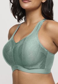 Lichtgroene sportbeha met een gestructureerde stof met geometrische patronen, brede bandjes en een gladde onderband voor ondersteuning.