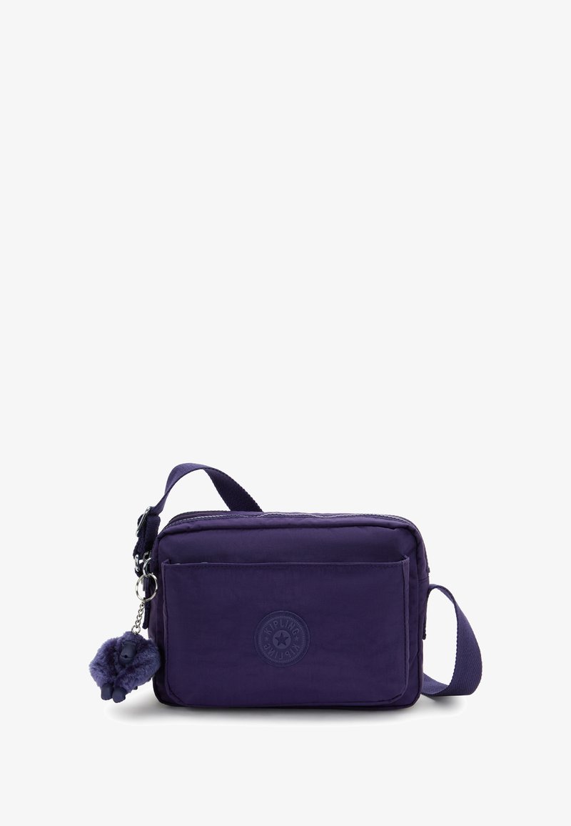 Bolso cruzado rectangular púrpura con bolsillo frontal, correa ajustable, compartimento principal con cremallera y un pequeño llavero de mono peludo adjunto.