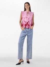 Rosa ermeløs topp med volanger, nøkkelhull-krage og rød blomsterbroderi. Kombinert med lyseblå vide jeans og svarte hæl mules.
