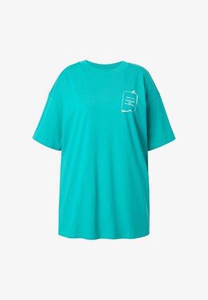 Camiseta de gran tamaño en color turquesa fabricada en algodón, con un diseño gráfico blanco en la zona del pecho izquierdo que incluye texto y detalles de acento.
