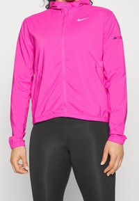 Chaqueta ligera rosa con cremallera y capucha, puños y dobladillo elásticos, de textura suave y con un pequeño bolsillo lateral. Detalle de logotipo plateado.