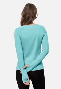 Vaaleansininen pitkähihainen paita hengittävästä materiaalista, jossa on pyöreä pääntie ja peukalon reiät hihoissa. Sileä pinta, urheilullinen istuvuus.