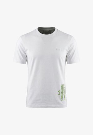 T-shirt Lacoste bianca a maniche corte con scollatura tonda, piccolo logo ricamato sul petto e scritta verde "LA CHEMISE LACOSTE PARIS" vicino all'orlo.