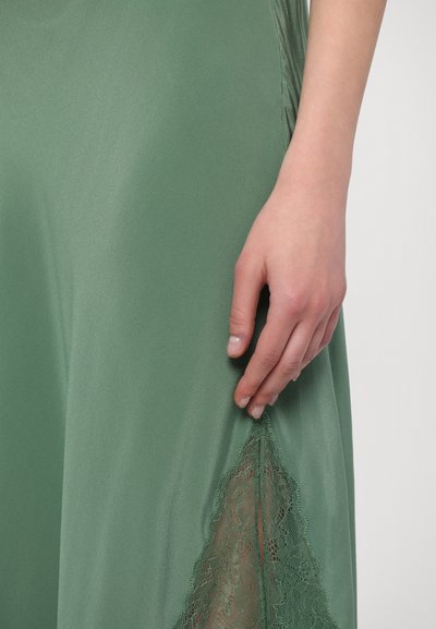 Groene satijnen jurk met een kanten accent aan de zoom. Soepele textuur met een lichte glans en een delicate, gedetailleerde kanten rand.