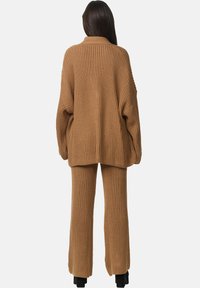 Bruine gebreide trui en bijpassende broek, met een geribbelde textuur, een relaxte pasvorm en lange mouwen voor comfort.