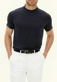 Navy short-sleeve t-shirt in soft fabric, round neckline, paired with white trousers and a black belt, featuring a silver buckle.