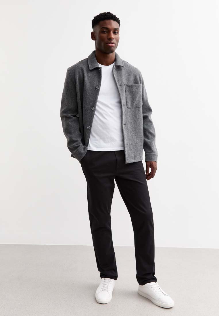 Chaqueta de mezcla de lana gris con cierre de botón y un bolsillo, usada sobre una camiseta blanca, combinada con pantalones negros y zapatillas blancas.