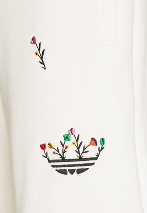 Tela blanca con un semicírculo a rayas negras bordado con flores y tallos en verde, rosa, rojo, amarillo y naranja.