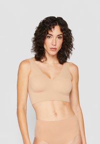 Beige, sömlös bralette med v-ringning och breda axelremmar, med en slät textur och minimalistisk design, i kombination med högmidjade trosor.