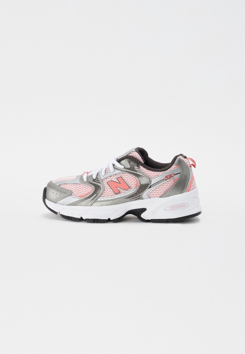 Chaussure de course avec tissu en mesh rose et superpositions argentées, semelle blanche, semelle extérieure noire, lacets blancs et logo rose "N" sur le côté.