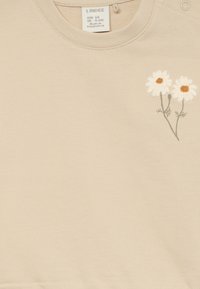 Helle beige Sweatshirt aus weichem Baumwollstoff. Auf der Front sind gestickte weiße Gänseblümchen mit braunen Zentren und grünen Stielen zu sehen.