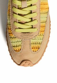 Zapatillas de ante beige con una parte superior de ganchillo texturizada en amarillo y verde, que presentan cordones verdes, punta redondeada y detalles en la suela de goma.