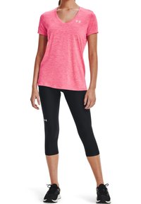 Camiseta rosa jaspeada con cuello en V hecha de una tela transpirable, combinada con leggins capri negros. Ambos presentan acentos de logo y un diseño ajustado.