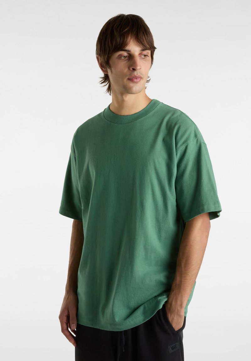 T-shirt vert oversize en coton, avec un col rond, des manches courtes et une texture lisse. Design simple sans motifs.