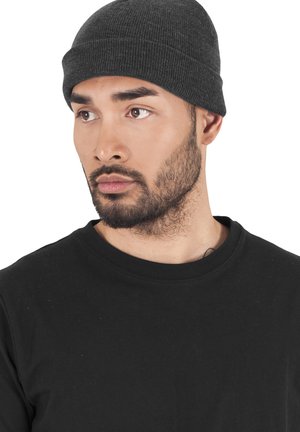 Gray ribbed beanie hat made of knit fabric, snug-fitting, with a subtle seam detail. Worn with a black crewneck t-shirt.