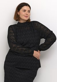 Czarna bluzka z koronką, z długimi rękawami i wysokim kołnierzem, z teksturowanym wzorem w zygzaki i luźnym krojem, w komplecie ze spódnicą w tym samym stylu.
