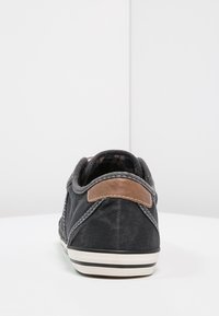 Tmavošedé volnočasové tenisky s bílou podešví a hnědým koženým patkem, z pohledu zezadu na bílé ploše na čistě bílém pozadí.