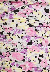 Ruchovaná látka s vícebarevným květinovým vzorem v růžové, fialové, žluté a černé barvě na bílém pozadí. Textura vypadá měkce.