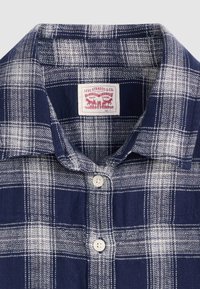 Camisa xadrez azul-marinho com tecido macio, fecho de botões, gola clássica e etiqueta vermelha da Levi Strauss & Co. com detalhes em branco.