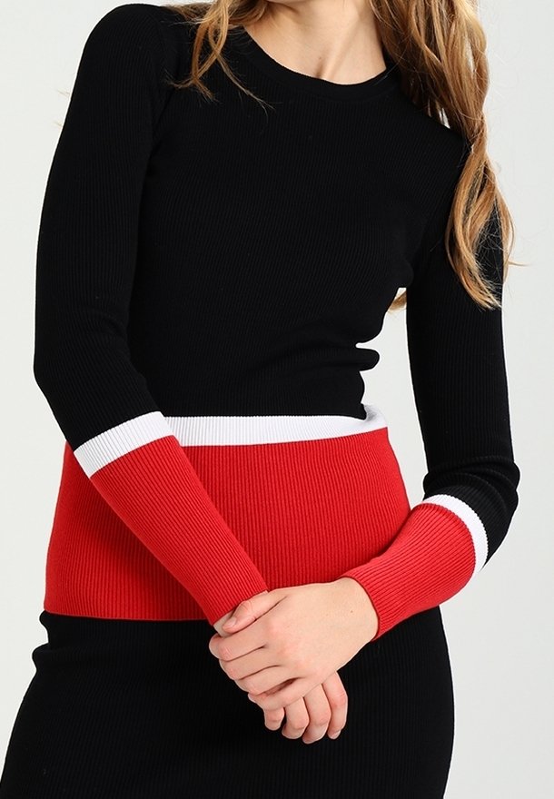 Schwarzes, geripptes Langarmoberteil mit einem rot-weißen gestreiften Bund und Ärmelbündchen, das ein figurnahes Design und ein strukturiertes Material hervorhebt.